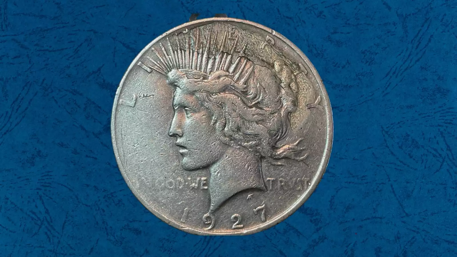 1927 Peace Dollar strike-through error showing smooth recessed patch on Liberty's portrait where a foreign object blocked the die during minting